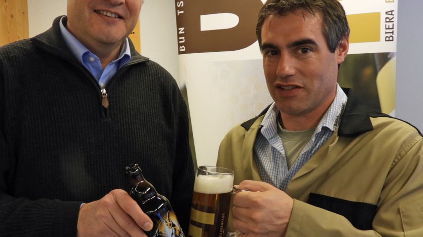 Bruno Güntensperger (a schnestra) da la «Liechtensteiner Brauhaus AG» e Reto Rauch, manader da gestiun da la Bieraria Tschlin SA, s’allegran da la nouva collavuraziun (fotografia: Annatina Filli).