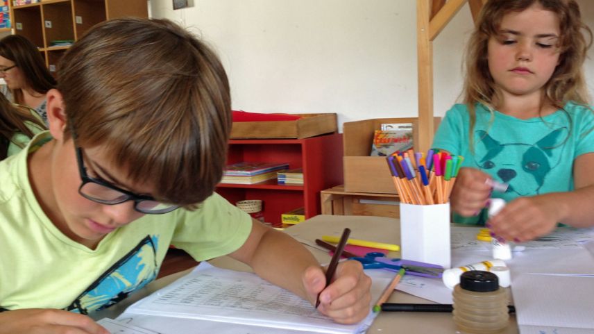 Tim e Julia Pfiffner da Wolfhausen imprendan insembel cun oters uffants e famiglias a scriver e discuorrer rumantsch a Scuol in ün cuors da la Lia Rumantscha (fotografia: Annatina Filli).