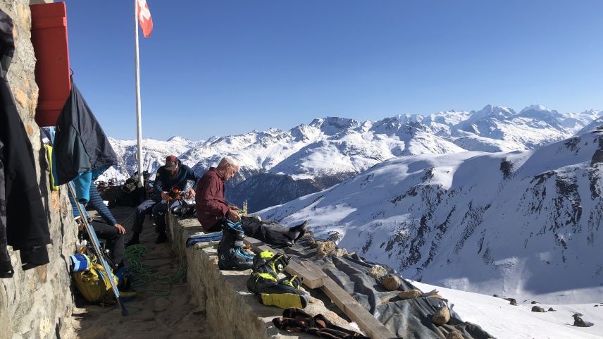 Die Tourengäste geniessen die Märzsonne auf der Terrasse der Es-cha Hütte und retablieren ihre Ausrüstung.