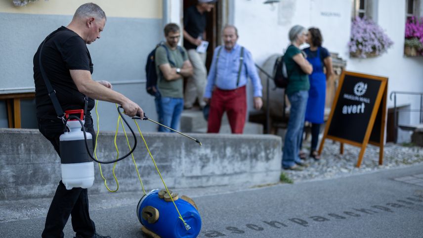 L’artist Pascal Lampert da Sta. Maria (a schnestra) ha performà davant il Muglin Mall sia inscripziun da «pasch» sülla via da Paclera (fotografia: Dominik Täuber). 