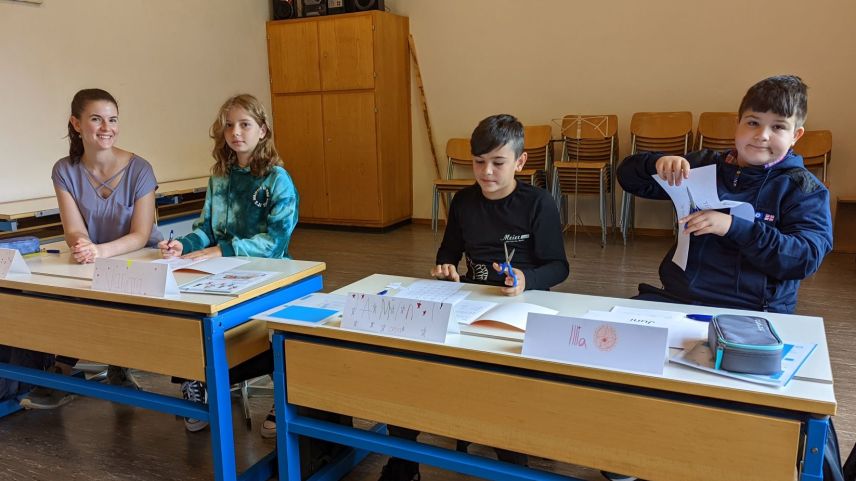 La magistra Grace Fasser cun Maria (5avla classa), Amin (7avla classa) ed Illya (5avla classa). I manca Varvara chi frequainta la prüma classa (fotografia: Thomas Brülisauer).