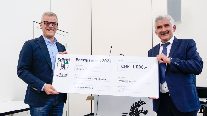 Heinz Gross, manader progets e logistica da l'OEE SA (a schnestra) survain dal president cumünal da Zernez scadent, Emil Müller, il schec dal premi d'energia 2021. fotografia: Jon Duschletta