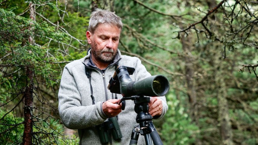 Biologe David Jenny beobachtet aus sicherer Entfernung ein Uhu-Weibchen mit Jungvogel. Foto: Jon Duschletta