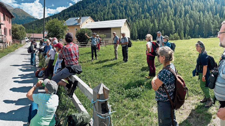 Duri Bezzola erläutert eine Inschrift, die auf dem hintersten Haus in Susauna steht. Sie verweist auf den Lawinenwinter 1950/51, als Teile des Hauses der grossen Lawine zum Opfer fielen. 	Foto: David Jenny