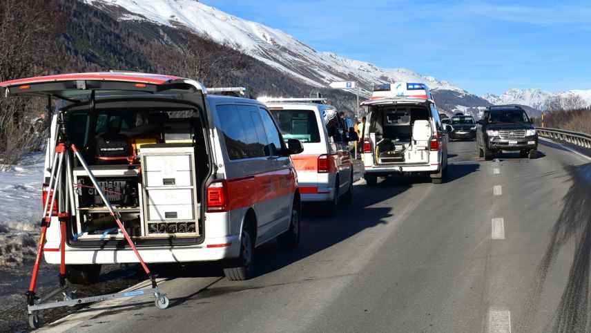 Auf der linken Seite stehen am Strassenrand drei Einsatzfahrzeuge der Rettungskräfte und der Polizei. Im Hintergrund ist ein am Unfall beteiligtes Fahrzeug zu erkennen (Foto: Kantonspolizei Graubünden).