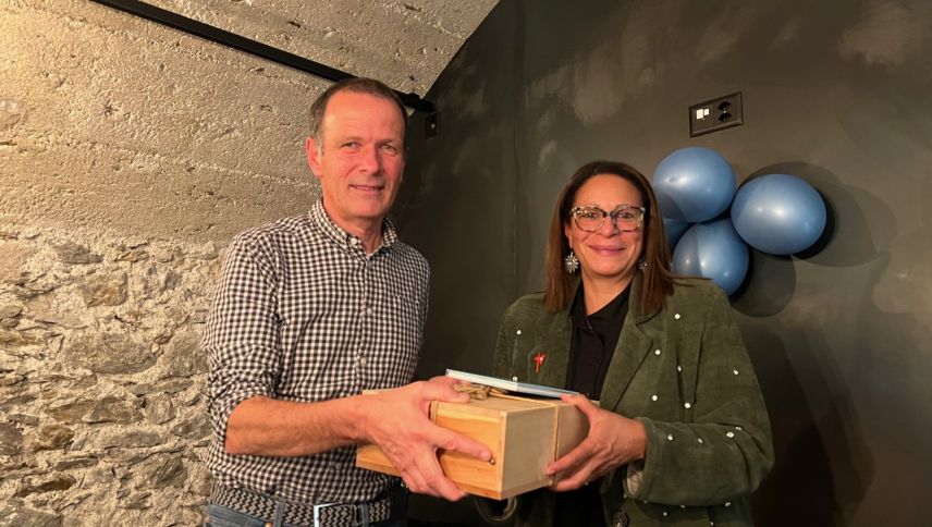 La presidenta dal Cumün da Val Müstair, Gabriella Binkert Becchetti, surdà ün regal a seis chanzlist pensiunà Not Manatschal (fotografia: Cumün da Val Müstair).