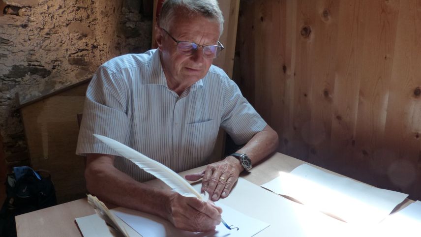 Theodor Gut, chi’d es commember dal cussagl da fundaziun dal museum Stamparia Strada, scriva culla penna d’ocha (fotografia: Flurin Andry).