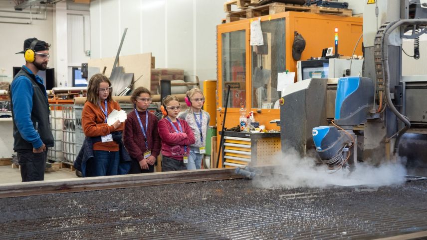 Jon-Corsin Neuhäusler (links) der Tschenett AG beobachtet mit MINT-Schülerinnen gespannt, wie ein Wasserstrahl die zuvor programmierten Dachteile ihres Vogelhäuschens aus einer Aluminiumplatte schneidet. Fotos: Jon Duschletta
