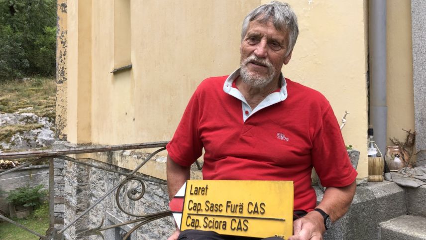 Arturo Giovanoli vor dem Eingang seines Wohnhauses mit einem gelben Wegweiser. Das Schild wurde ihm geschenkt.             Foto: Marie-Claire Jur