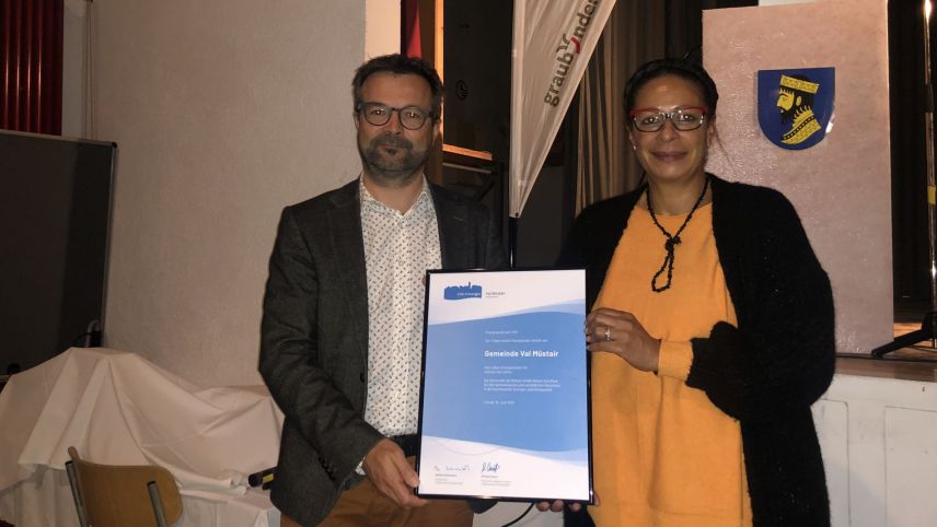 Michael Casutt (a schnestra) surdà a Gabriella Binkert Becchetti il label «Cità d’energia» pels prossems quatter ons (fotografia: David Truttmann).