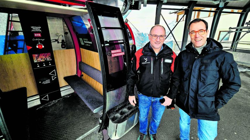 Il directer da las Pendicularas Scuol Andri Poo (a schnestra) ed il directer da RTR Nicolas Pernet preschaintan  la cabina chi spordscha in avegnir cuors da rumantsch (fotografia: RTR).