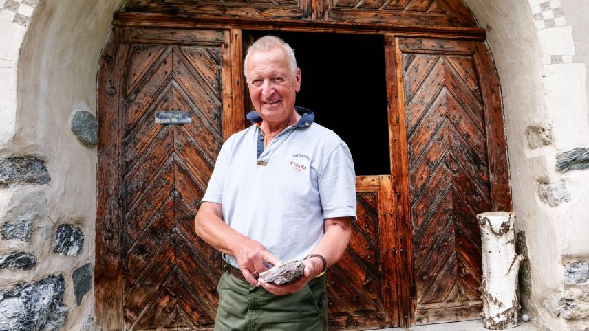 Der emeritierte Geologieprofessor Christian Dullo vor dem altehrwürdigen Haus der Stiftung A.P. Laudenbacher in La Punt Chamues-ch mit einem aus marinen Mikroorganismen entstandenen Stück Radiolarit. Foto: Jon Duschletta
