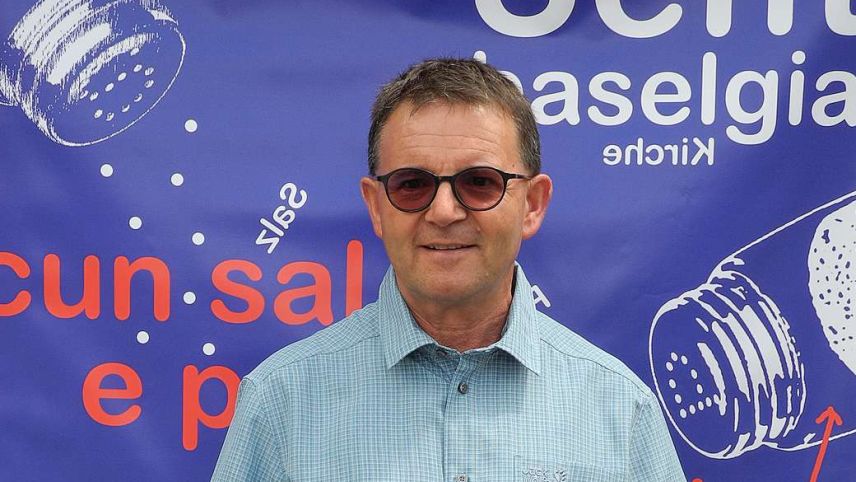 Andri Gritti davant il placat da l’arrandschamaint actual, il festival cultural «cun sal e paiver» ch’el ha organisà. fotografia: Gianna Bettina Gritti