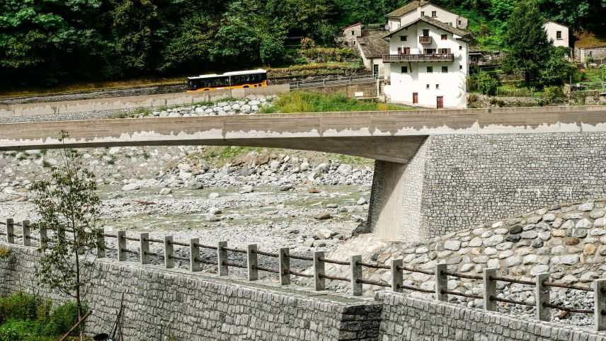 Blick von Bondo in Richtung Sottoponte und der neuen, um über fünf Meter erhöhten Kantonsstrassenbrücke Bondasca (Bildmitte) über dem Zusammenfluss von Maira und Bondasca sowie dem neuen Dammweg entlang des Rückhaltebeckens im Vordergrund. 