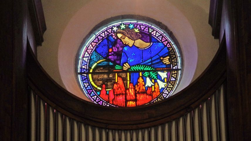 Das runde Glasfenster «La Cretta» über der Orgel der Kirche Zuoz schuf Giuseppe Scartezzini im Auftrag von Gordon Spencer im Andenken an dessen verstorbene Frau. Foto: Jürg Keller