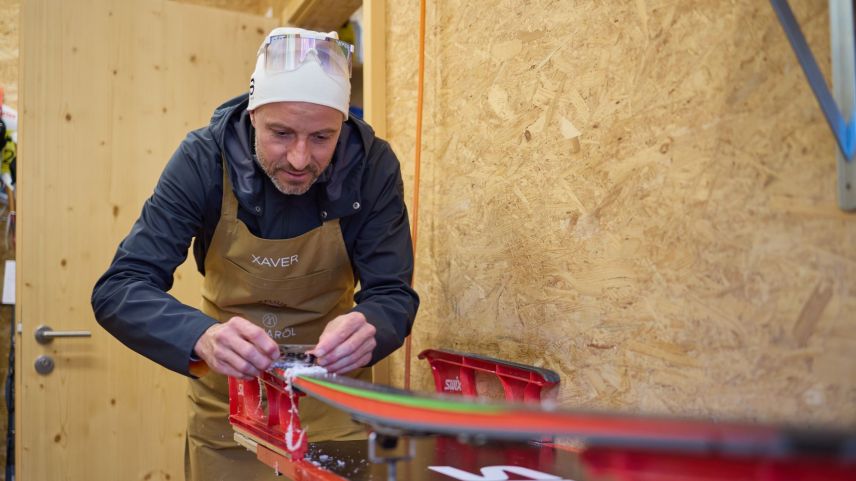 Xaver Frieser sgratta giò tuot la tschaira cun üna nizza da plastic e prepara ils skis pel «Passlung Martina – Scuol» (fotografia: Michael Steiner).