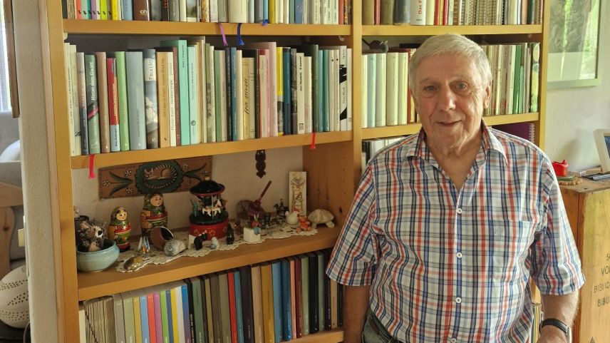 Hans Fäh davant sia biblioteca rumantscha (fotografia: Laura Schütz).