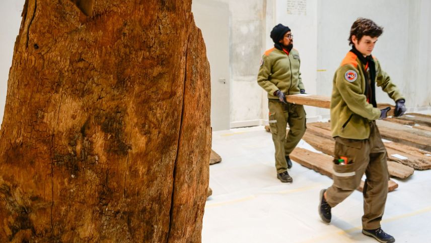 Arjuna Sivalingam (links) und Lezi Flepp tragen vorsichtig ein Holzstück ums andere in den Ausstellungsraum der Quellfassung.