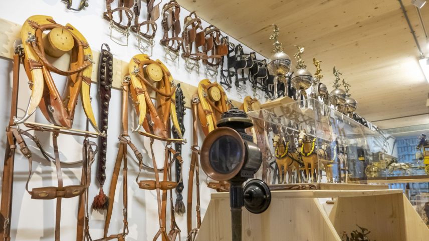 Bündner Geschirre an der Wand, diverse Kutschenlampen, Halfter und auch ein Postkutschen-Modell sind Teil der Sammlung.