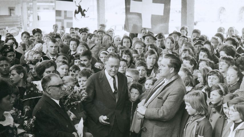 Festbetrieb rund um den Bahnhof St. Moritz anlässlich der Taufe der neuen RhB-Lokomotive am 14.04.1965. Der Anlass hat viele Gäste angelockt. 