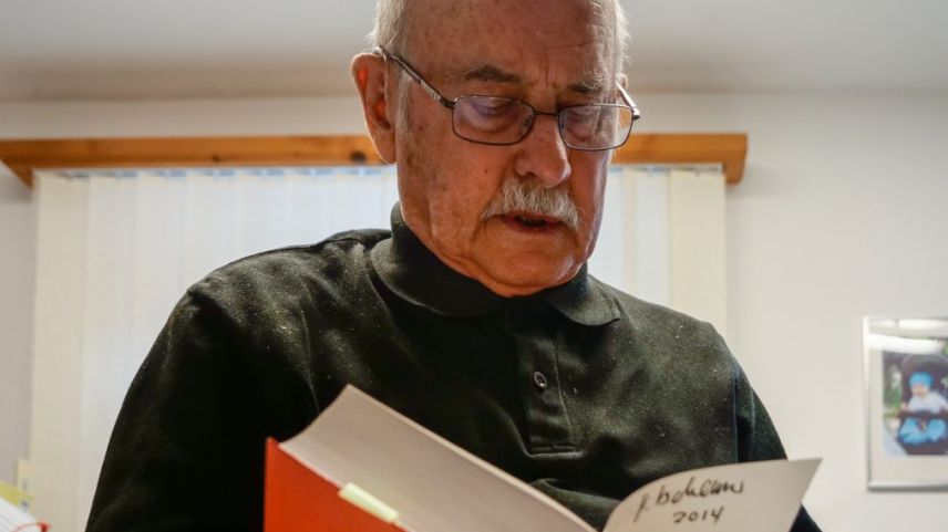 Il teolog e romanist Gion Tscharner sföglia in «seis» dicziunari puter–tudais-ch, al qual el s’ha dedichà ils ultims trais decennis (fotografia: Jon Duschletta).