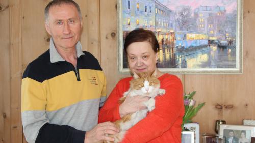 Irina Polhul und Anatolij Svartschevskij mit ihrer Katze Michelle in Samedan. Das Gemälde im Hintergrund zeigt die Stadt Winnyzja, in der Züritrams verkehren. 
