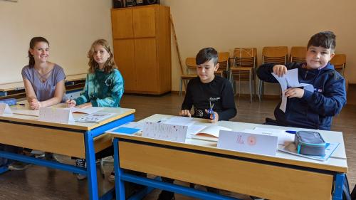 La magistra Grace Fasser cun Maria (5avla classa), Amin (7avla classa) ed Illya (5avla classa). I manca Varvara chi frequainta la prüma classa (fotografia: Thomas Brülisauer).