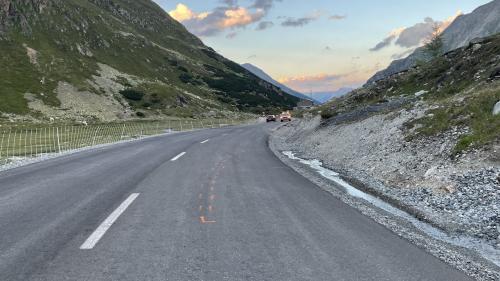 Die Rechtskurve mit auf der Strasse eingezeichneten Unfallspuren. In Entfernung ein Polizeiauto. Foto: Kantonspolizei Graubünden