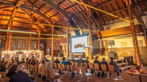 Nur gut 50 Personen wollten am Dienstagabend die Infoveranstaltung vor Ort in der Reithalle mitverfolgen. Rechts das Modell der wieder stützenfreien Reithalle nach der Sanierung. Foto: Reto Stifel, Visualisierung Gemeinde St. Moritz 