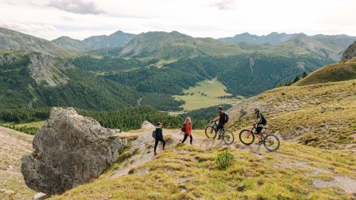 Viandants e bikers i’l Parc da natüra Biosfera Val Müstair chi piglian resguard l’ün a l’oter (fotografia: Doyenne).