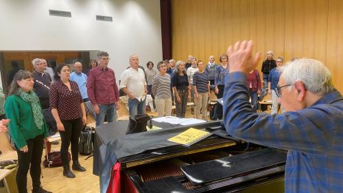 Il dirigent Jachen Janett ed üna part dal cor pro la penultima prouva in sonda passada a Sent (la terza da schnestra es la solista Sara Bigna Janett, la figlia dal dirigent). (fotografia: Flurin Andry)