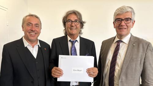 Il cusglier guvernativ Jon Domenic Parolini (a dretta) ha surdat il premi d'arcugnuschentscha dal chantun Grischun a Reto Mayer. A schnestra Andy Kollegger da l'Uniun da musica chantunala (fotografia: Nicolo Bass)