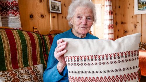 Laura Pfäffli in sia stüva a Sta. Maria cun ün plümatsch tessü da seis temp cun saida da Bourette (fotografia: Jon Duschletta).