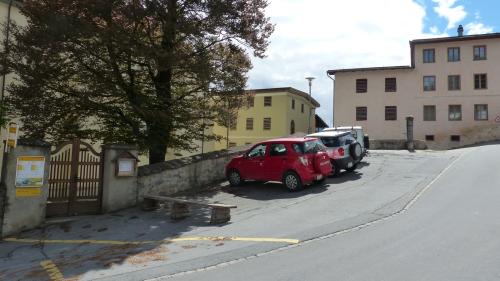 Las unicas plazzas da parcar publicas sun a Ramosch sün Plaz, sper la baselgia. Davovart as vezza chasas cun tablats tipics pel cumün (fotografia: Flurin Andry).