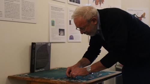 Il linguist Chasper Pult a metter insembel il puzzle dal Rosetta Stone. Üna tela üsaglia druvess que tenor el eir per decoder il retic (fotografia: Martin Camichel).