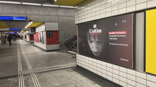 Tuot sulet penda il placat da «L’ultim Rumantsch» i’l suotpassagi da la staziun da Cuoira. La nouva seria ficziunala dad RTR es gnüda propagada fermamaing  i’l Grischun (fotografia: David Truttmann)