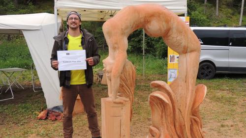 L’artist victur Gerald Lutz cun sia sculptura «Weltenbrücke/Nixe» (fotografia: Benedict Stecher).