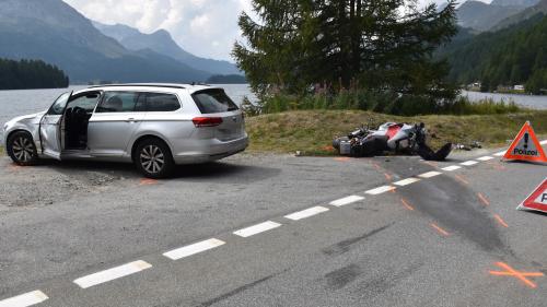 as Auto auf dem Ausstellplatz. Dahinter das am Boden liegende Motorrad. Im Hintergrund der Silser See (Foto: Kantonspolizei Graubünden).