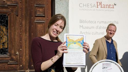 Diana Pedretti declarand l‘aquarel da Clara Porges il cudesch da giasts da la Pensiun Chesa Surlej (fotografia: Gian-Nicola Bass).