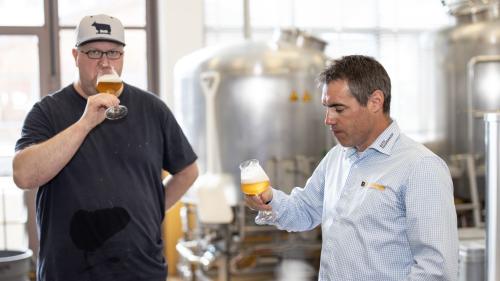 Il bierer Christian Schneider (a schnestra) e’l mainagestiun Reto Rauch prouvan co cha la biera gusta (fotografia: Dominik Täuber).